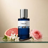 Aromara Vanilla Bliss Extrait perfume bottle on glass shelf with grapefruit, white jasmine, vanilla pod and pink rose on soft cream background