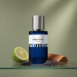 Aromara Lisbon Woods Extrait perfume bottle on glass shelf with bergamot, cedar plank, dried lavender and charred wood on soft sage green background