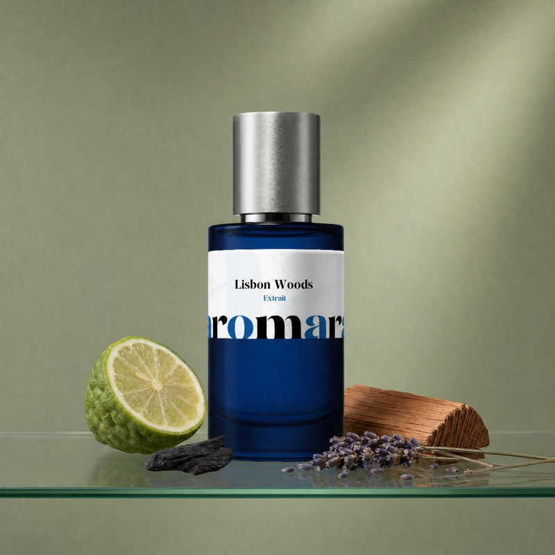 Aromara Lisbon Woods Extrait perfume bottle on glass shelf with bergamot, cedar plank, dried lavender and charred wood on soft sage green background