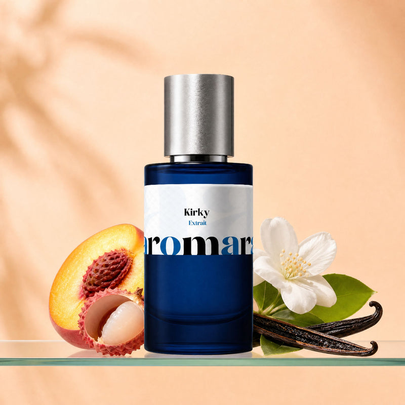 Aromara Kirky Extrait perfume bottle with halved peach, lychee fruit, white jasmine flower, and vanilla pod on a clear glass shelf, warm peach-cream backdrop
