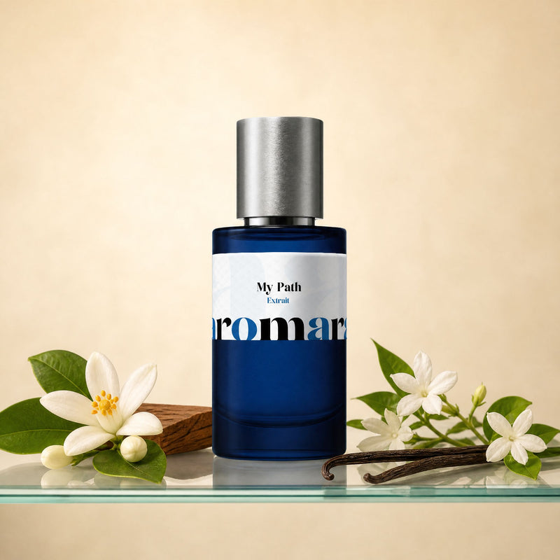 Aromara My Path Extrait perfume bottle on glass shelf with orange blossom, white jasmine, vanilla pod and sandalwood on soft cream background