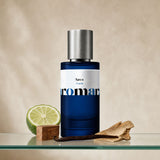 Aromara Savo Extrait perfume bottle on glass shelf with bergamot, cedarwood block, vanilla pod and sandalwood on soft warm beige background
