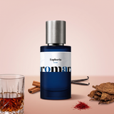 Euphoria by Aromara on a pale blush rose and soft cinnamon rose background with a glass of rum, tobacco leaves, cinnamon sticks, vanilla pods and saffron. 35% Extrait, inspired by Initio Side Effect.