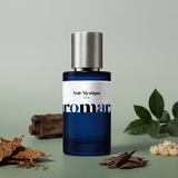 Noir Mystique by Aromara on a pale eucalyptus grey to soft smoky moss green background with tobacco leaves, oud wood chips, frankincense resin, dark wood and green leaves. 35% Extrait, inspired by Nasomatto Black Afgano.