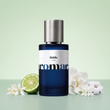 Riddle by Aromara on a pale celadon green to soft sage mint background with a halved bergamot, neroli blossoms, a white magnolia, jasmine and cotton. 35% Extrait, inspired by Prada Paradoxe.