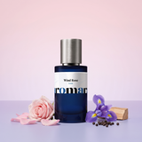 Wind Rose by Aromara on a pale petal pink to iris lilac background with a pink rose, rose petals, an iris flower, black peppercorns and cedarwood. 35% Extrait, inspired by Louis Vuitton Rose des Vents.