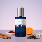Violet Stain by Aromara on a pale lavender to dusky violet background with cinnamon sticks, saffron threads, a halved mandarin, agarwood chips and orange blossom. Up to 35% Extrait, inspired by BORNTOSTANDOUT Purple Stain.