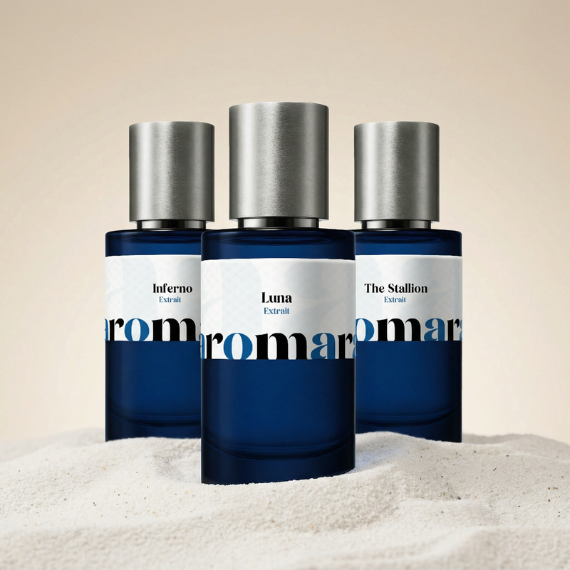 Three blue perfume bottles with silver caps on a beige sand-like background